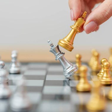 Satranç tahtası yarışmasında el hareketli altın satranç kralı figürü ve şah mat rakibi. Strateji, Başarı, Yönetim, İş Planlama, Galibiyet, Karışıklık, Ticaret Savaşı ve Liderlik Konsepti
