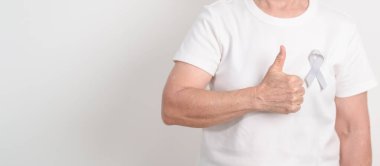 Mayıs Kanser Farkındalığı ayı için gri kurdeleli yaşlılar ve Astım Bilinci, Yaşam İnsanları Destekleme Kurdelesi. Sağlık ve Şubat Dünya Kanser Günü