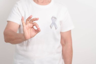 Mayıs Kanser Farkındalığı ayı için gri kurdeleli yaşlılar ve Astım Bilinci, Yaşam İnsanları Destekleme Kurdelesi. Sağlık ve Şubat Dünya Kanser Günü