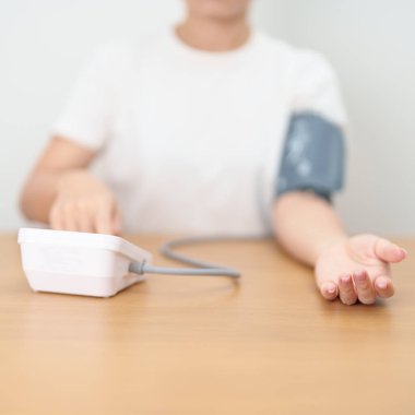 Kan basıncı monitöründen kadın kelepçeyle kan basıncını ölçüyor. Sistolik, SYS, Diyastolik, DIA, Nabız, Hipertansiyon, Hipotansiyon, Kalp hızı, Kardiyovasküler Hastalık ve Mayıs Dünya Hipertansiyon Günü