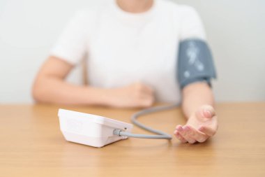 Kan basıncı monitöründen kadın kelepçeyle kan basıncını ölçüyor. Sistolik, SYS, Diyastolik, DIA, Nabız, Hipertansiyon, Hipotansiyon, Kalp hızı, Kardiyovasküler Hastalık ve Mayıs Dünya Hipertansiyon Günü