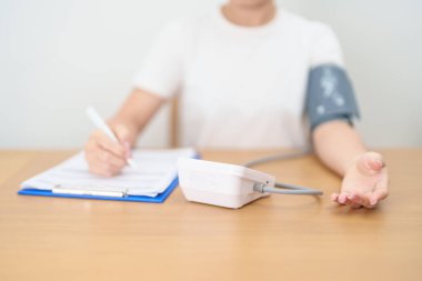 Kan basıncı monitöründen kadın kelepçeyle kan basıncını ölçüyor. Sistolik, SYS, Diyastolik, DIA, Nabız, Hipertansiyon, Hipotansiyon, Kalp hızı, Kardiyovasküler Hastalık ve Mayıs Dünya Hipertansiyon Günü