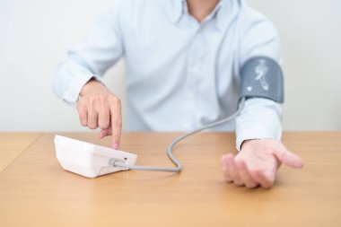 Kan basıncını ölçen adam kelepçeyle kan basıncını ölçüyor. Sistolik, SYS, Diyastolik, DIA, Nabız, Hipertansiyon, Hipotansiyon, Kalp hızı, Kardiyovasküler Hastalık ve Mayıs Dünya Hipertansiyon Günü