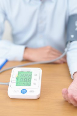 Kan basıncını ölçen adam kelepçeyle kan basıncını ölçüyor. Sistolik, SYS, Diyastolik, DIA, Nabız, Hipertansiyon, Hipotansiyon, Kalp hızı, Kardiyovasküler Hastalık ve Mayıs Dünya Hipertansiyon Günü