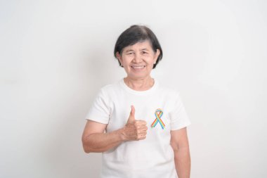 Haziran Gurur Ayı, Nisan Otizm Bilinci, Kanser Farkındalığı, Şubat Dünya Kanser Günü, Ekim Dünya Bakımevi ve Palyatif Bakım Günü konsepti için LGBTQ Gökkuşağı kurdelesine sahip yaşlılar