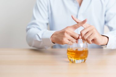 Bir bardak viskiyi reddetmek için el hareketi yapan sağlıklı bir adam alkollü içeceğe, alkolizme ve bağımlılık konseptine hayır der. Sorumlu adam araba kullanmadan önce içkiyi reddeder ve içkiyi bırakır.