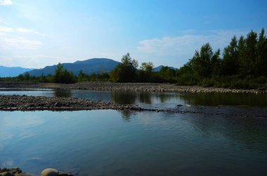 Dağları, ormanı ve önünde bir nehri olan bir manzara. Güzel manzara.