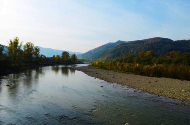 Dağları, ormanı ve önünde bir nehri olan bir manzara. Güzel manzara.