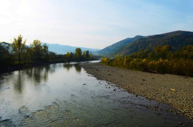 Dağları, ormanı ve önünde bir nehri olan bir manzara. Güzel manzara.