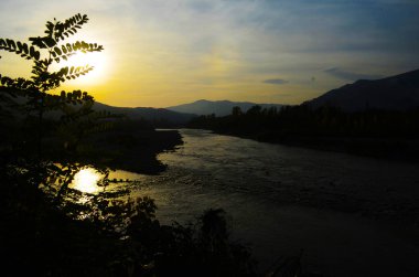 Dağları, ormanı ve önünde bir nehri olan bir manzara. Güzel manzara.