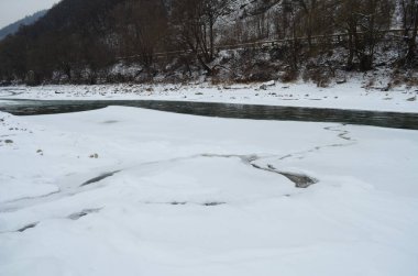 Kış zamanı dağ nehri. Ladin ormanı ve karla kaplı kıyısı olan Karpatya manzarası. Ulusal Park, Ukrayna