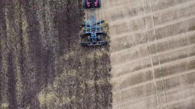 Harrows 'lu kırmızı traktör tarımı hasat için hazırlıyor. Drone hava perspektifi görünümü.