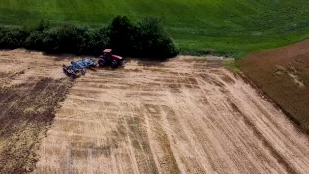 収穫物を植えるための農地を準備する矢印付きの赤いトラクター ドローンの空中展望 — ストック動画