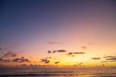 Güneş batarken dramatik deniz kıyısı günbatımı bulutlu gökyüzünde turuncu ve canlı mavilerle