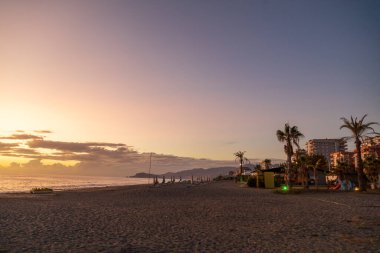 Güneş batarken dramatik deniz kıyısı günbatımı bulutlu gökyüzünde turuncu ve canlı mavilerle