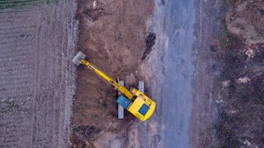 Kazıcı ya da toprak taşıyıcı yola yeni bir katman koymadan önce yan yük üzerinde toprak kazıyor..
