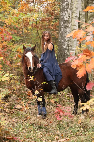Linda chica con caballo marrón en otoño — Foto de Stock