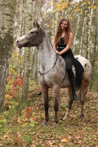 Jong meisje met appaloosa paard in de herfst — Stockfoto