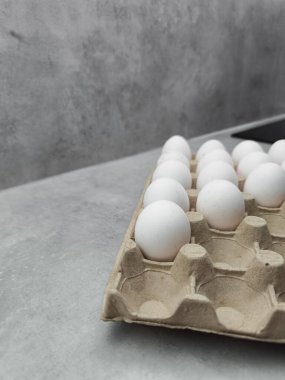 Mutfak tezgahında dinlenen bir karton taze beyaz yumurta Paskalya kahvaltısı, krep pişirme ya da diğer aşçılık icatları için hazır, resim ve tatil sanatları için hazır.
