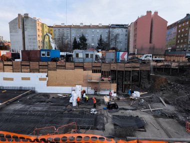 Prague, Czech republic - February 25, 2025: Construction workers building the foundation of a new residential building in a bustling urban area surrounded by existing apartments vysocany