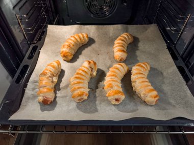 Altı tane yumuşak pastaya sarılmış dana sosisi, yerli bir fırının içindeki tepside pişirme, mutfağı lezzetli bir aromayla doldurma.