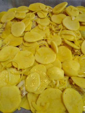 Dilimlenmiş patates ve soğan fırında pişirilmeye hazır lezzetli ve rahatlatıcı bir yemek.