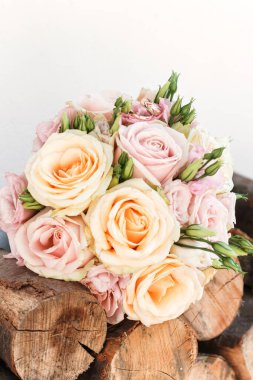 Şeftali ve pembe güller ve lisianthus çiçekleriyle birlikte çarpıcı bir düğün buketi oluştururlar, kırsal ağaçlardaki çiçeklerin arasına yerleştirilmiş iki yüzük, romantizm saçar