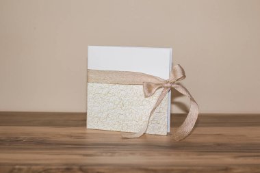 Altın madalyalı beyaz bir düğün kitabı ve ahşap bir masanın üzerinde duran saten bir kurdele. Konukların imzalaması ve mutlu çift için dileklerini bırakmaları için hazır.