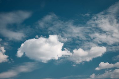 Beyaz bulutlar derin mavi bir gökyüzünde sürükleniyor, sakin ve huzurlu bir atmosfer yaratıyor, arka plan ya da duvar kağıdı tasarımları için mükemmel, sükunet ve sükuneti çağrıştırıyor. Yüksek kalite fotoğraf