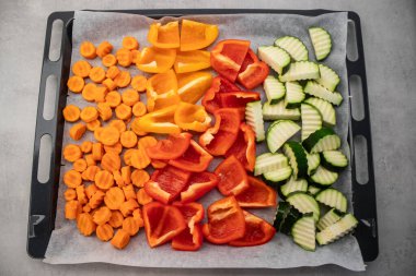 Renkli dilimlenmiş havuç, sarı ve kırmızı dolma biber ve kabak dilimlenmiş parşömen örtüsü üzerinde canlı bir yemek sahnesi yaratmak için hazır. Yüksek kalite fotoğraf