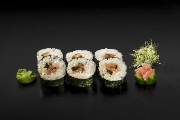 Deliciosos pequeños rollos de sushi decorados con ensalada de algas marinas y — Foto de Stock