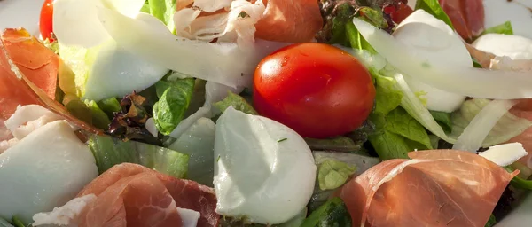 Close-up van groene salade met prosciutto en kerstomaatjes — Stockfoto