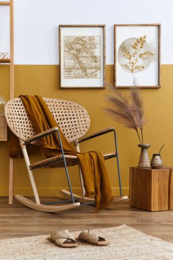 Dizayn edilmiş rattan koltuk, iki poster çerçevesi, bitkiler, küp, soluk ve kişisel aksesuarlar ve bal sarısı ev dekoru ile oturma odasının şık kompozisyonu. Şablon.