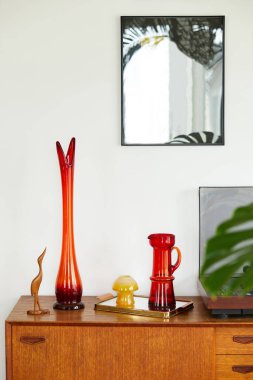 Ahşap dolapta retro kırmızı vazo, vinil kaydedici ayna modeli ve zarif kişisel aksesuarlarla klasik kompozisyon. Şablon.
