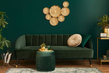 Modern iç tasarımı, yeşil kadife kanepesi, kahve masası, puf, altın dekorasyon, bitki, lamba, halı, yastıklar ve zarif aksesuarları olan lüks oturma odası. Şablon. 