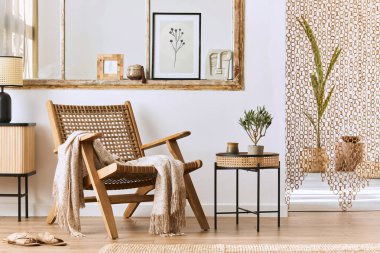 Şık rattan koltuklar, tasarım mobilyaları, kurutulmuş çiçekler, poster çerçeveleri, ahşap döşemeler, dekorasyon ve zarif kişisel aksesuarlarla eşsiz bir oturma odası. Modern ev. Şablon.