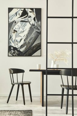 Ahşap aile masası, siyah sandalyeler, kahve fincanları, vazoda tropikal yaprak, duvarda soyut resimler ve zarif aksesuarlar. Modern ev dekorasyonu. Şablon.