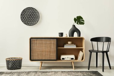 Modern tarzda tasarlanmış ahşap klozet, siyah sandalye, rattan dekorasyonu, fotokopi alanı, kitap, halı ve ev dekorunda zarif aksesuarları olan eşsiz oturma odası. Şablon.