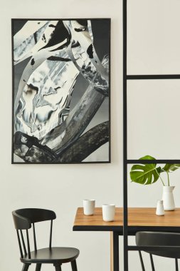 Ahşap aile masası, siyah sandalyeler, kahve fincanları, vazoda tropikal yaprak, duvarda soyut resimler ve zarif aksesuarlar. Modern ev dekorasyonu. Şablon.