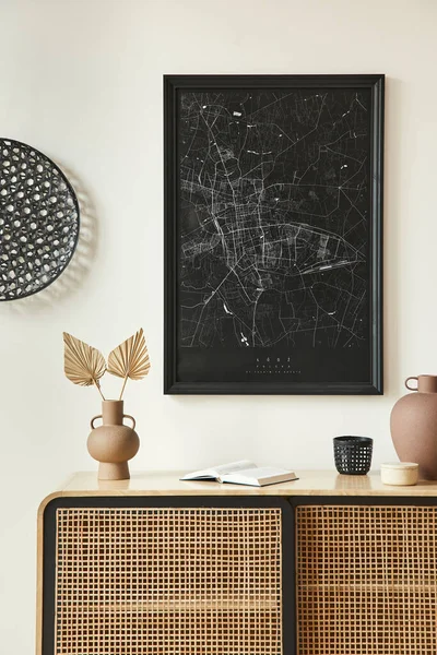 Minimalist composition of living room interior with black mock up poster map, wooden commode, black round decoration, leaf in vases and elegant personal accessories. Template.