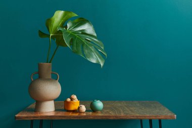 Ceviz masalı iç mekan konsepti, vazoda tropikal yaprak, seramik kap ve modern klasik ev dekorunda zarif aksesuarlar. Yeşil duvar. Boşluğu kopyala.