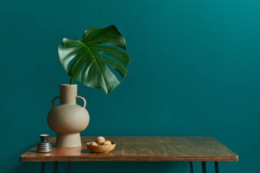 Ceviz masalı iç mekan konsepti, vazoda tropikal yaprak, saat ve modern klasik ev dekorunda zarif kişisel aksesuarlar. Yeşil duvar. Boşluğu kopyala.