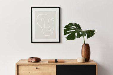 Poster çerçevesi, ahşap klozet, kitap, seramik vazoda tropikal yaprak ve zarif kişisel aksesuarları olan şık bir oturma odası. Minimalist ev dekorasyonu konsepti. Şablon.