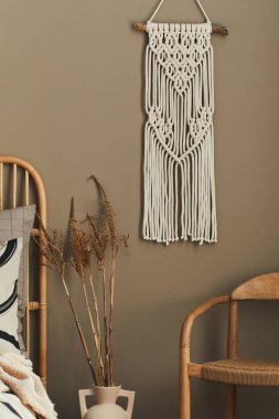 Tasarım dekorasyonu, nötr makrome, vazoda kurumuş çiçekler, sandalye, güzel yatak çarşafları, yastıklar ve kişisel aksesuarları olan şık bir yatak odası. Şablon.