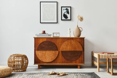 Modern ev dekorunda oturma odasının şık İskandinav kompozisyonu, siyah poster çerçeveleri, rattan puf, saat, ahşap tabure, kitap, dekorasyon ve kişisel aksesuarlar..