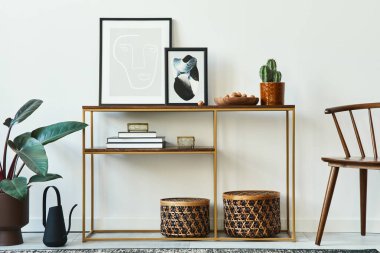 Model çerçeveler, ahşap konsol, sandalye, bitki, rattan sepetleri, bitki, halı ve ev dekorunda kişisel aksesuarları olan şık bir oturma odası konsepti. Şablon.