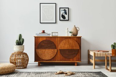 Şık İskandinav kompozisyonu tasarım klozeti, siyah poster çerçeveleri, rattan puf, kanepe, kitap, dekorasyon ve modern ev dekorasyonu kişisel aksesuarlar.