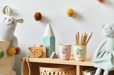 Şık İskandinav bebek odası oyuncakları, peluş hayvan, fotoğraf makinesi ve çocuk aksesuarları. Samimi dekorasyon ve beyaz duvara pamuk topları asmak. Boşluğu kopyala.