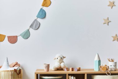 Şık İskandinav bebek odası oyuncakları, peluş hayvan, fotoğraf makinesi, oyuncak bebek ve çocuk aksesuarları. Samimi dekorasyon ve beyaz duvara pamuk topları asmak. Boşluğu kopyala.
