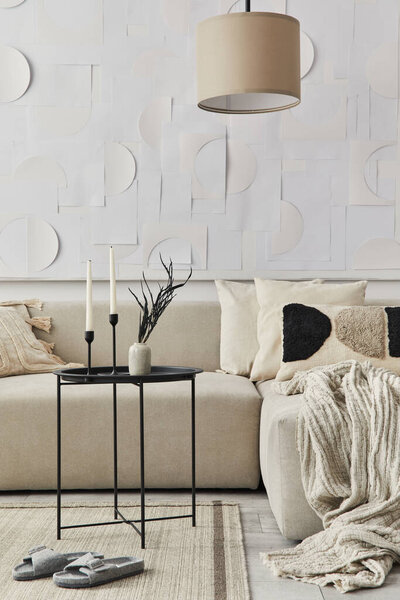 Stylish composition at fancy interior with black coffee table, dried flowers in vase, candle stick, pillow, blanket, art painitngs and book in modern home decor. Details. Template.